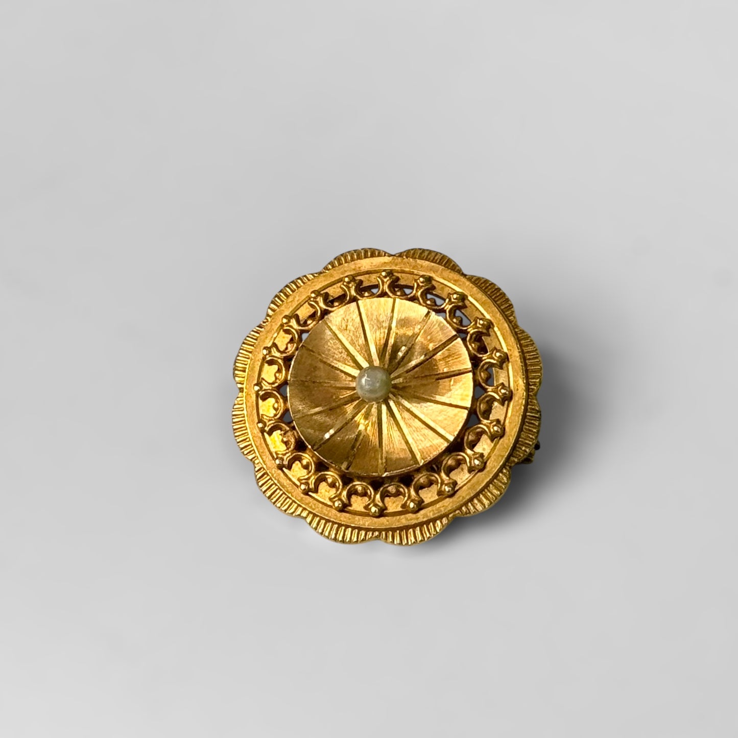 Round golden brooch with pearl